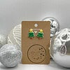 Handmade Christmas tree earrings on a card, surrounded by silver ornaments.