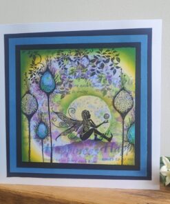 A fairy with wings sits on the ground in a colorful floral scene, framed with blue and black borders, accompanied by white flowers.