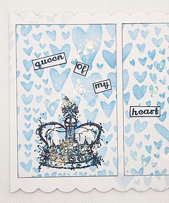 A handmade card with blue hearts, a crown, and text reading "queen of my heart" on a white scalloped border.