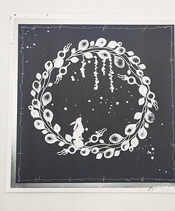 Illustrative white wreath with leaves, berries, and a rabbit on a dark background within an abstract border design.