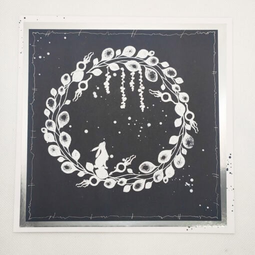 Illustrative white wreath with leaves, berries, and a rabbit on a dark background within an abstract border design.