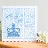 Greeting card with a blue crown, surrounded by hearts, and the text "queen of my heart." White flowers on a wooden surface.