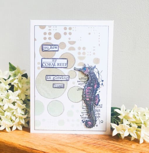 Handmade card with a seahorse and text: "You are my coral reef in glowing hues," surrounded by flowers.