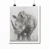 Black and white illustration of a rhinoceros standing on grassy terrain, clipped to a white frame and suspended against a plain background.