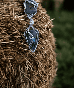 Handcrafted boho pendant with black and white striped stone hangs on a haystack. Statement jewellery with natural stone.