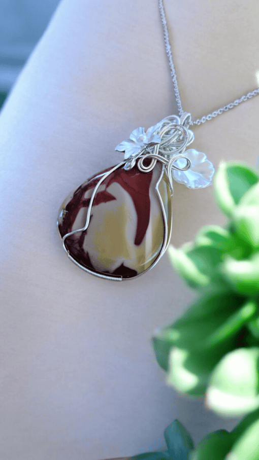 Elegant wire wrap jewelry designs featuring a handmade pendant with a red and yellow stone, adorned with delicate flowers.