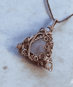 Handmade wire-wrapped jewellery featuring a floral design with a gray stone and intricate copper detailing, ideal for gifts.