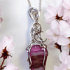 Silver chain necklace with intricate wire wrap design, featuring a pink and purple striped stone pendant, surrounded by cherry blossoms.