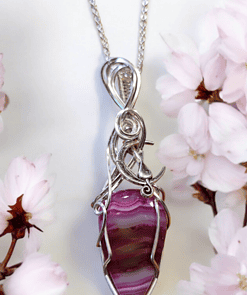 Silver chain necklace with intricate wire wrap design, featuring a pink and purple striped stone pendant, surrounded by cherry blossoms.