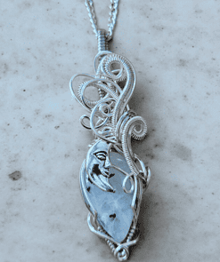 Intricate silver wire-wrapped pendant featuring a crescent moon face design, hanging on a silver chain.