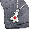 Silver necklace with a star and three gems, featuring a red central gem, displayed on a dark textured background.