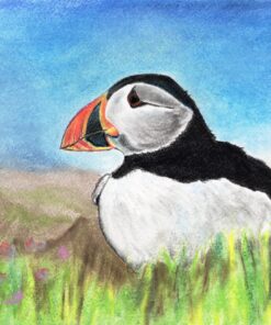 A puffin with a colorful beak is perched in tall grass, with a bright blue sky and distant mountains in the background.