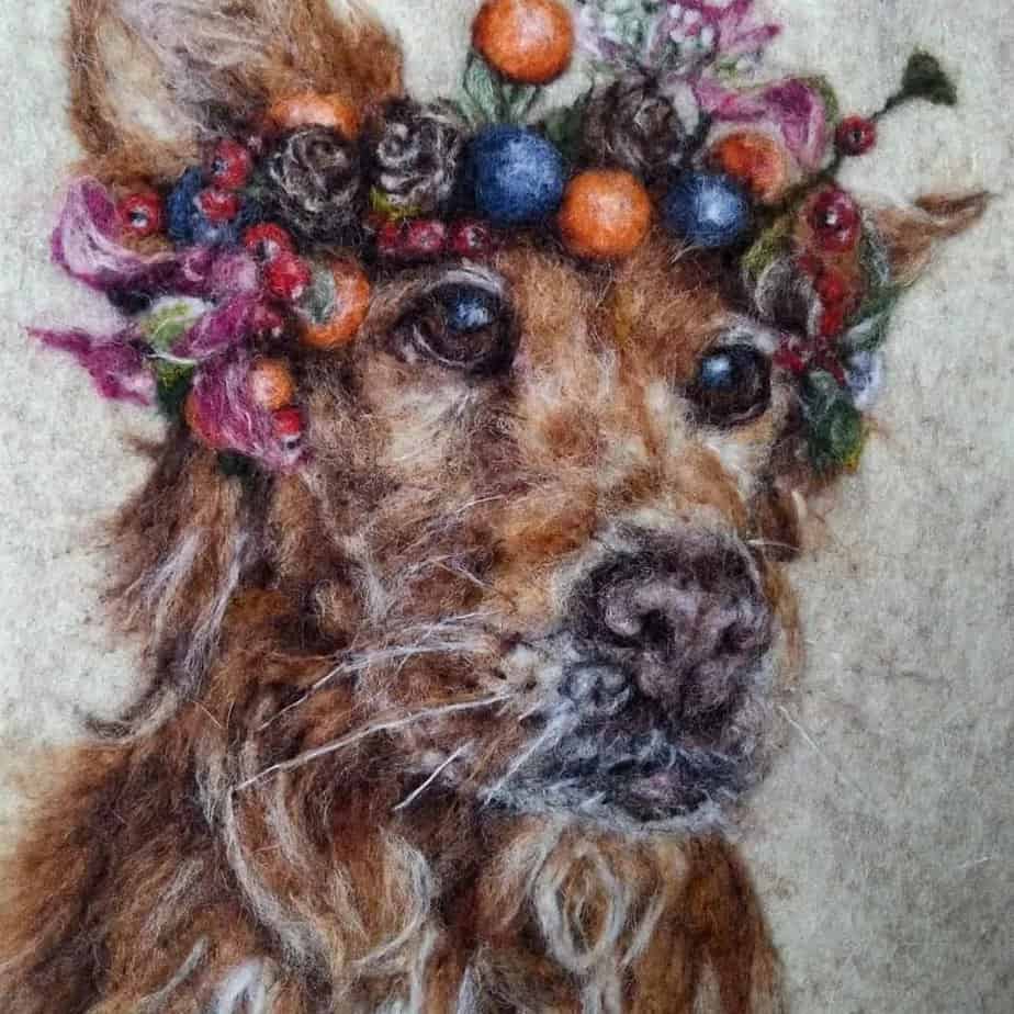 Needle felted dog portrait with a wreath of colorful flowers and berries around its head. Realistic detail and vibrant colors.