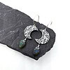 Oxidized silver earrings with floral patterns and leaf-shaped labradorite dangles, displayed on a dark stone surface.