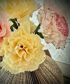 Close-up of colorful paper flowers, including pink, yellow, and white, in a detailed, textured design.