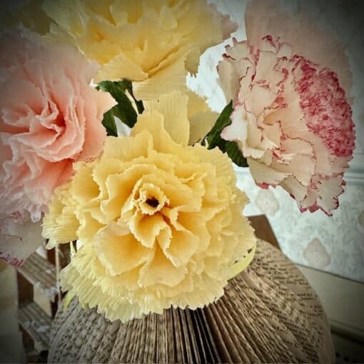 Close-up of colorful paper flowers, including pink, yellow, and white, in a detailed, textured design.